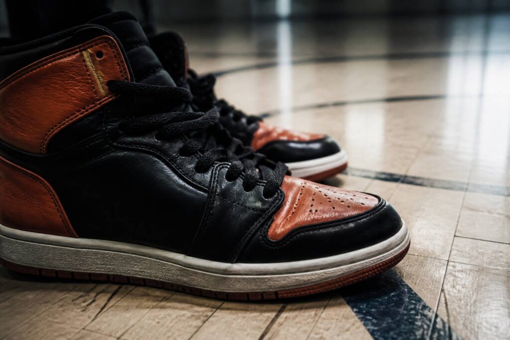 Paire de baskets de basket vintage rouges et noires posées sur le parquet d'un gymnase