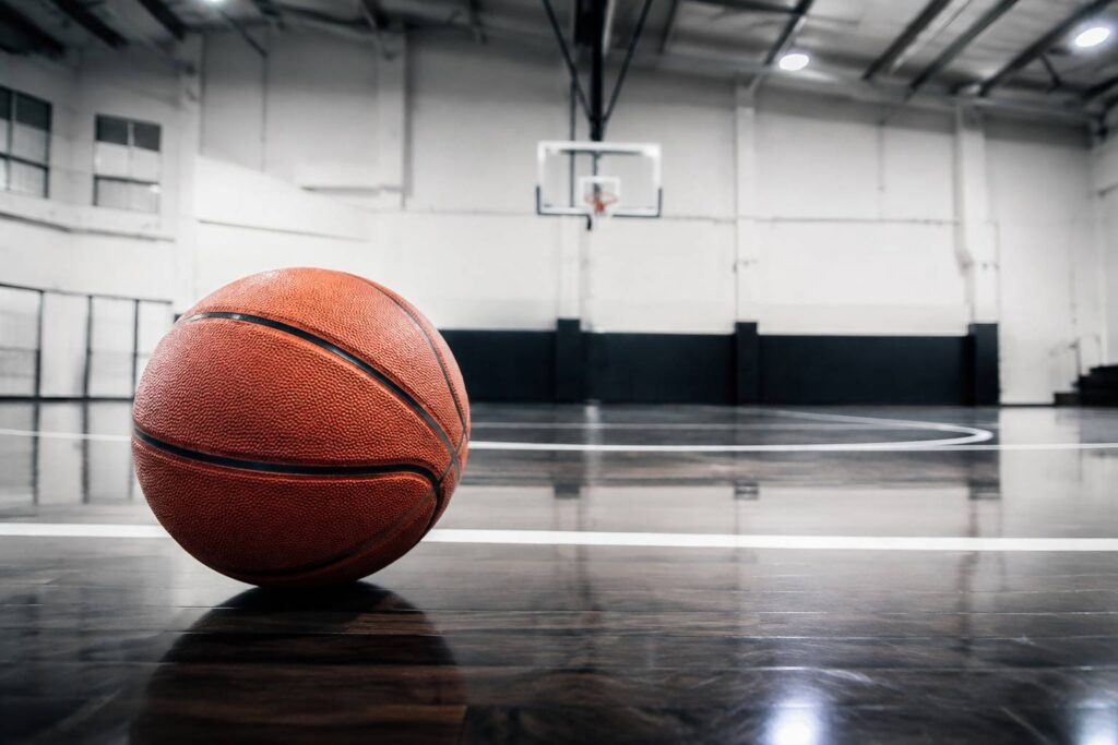 Ballon de basket posé sur le parquet d'un gymnase éclairé