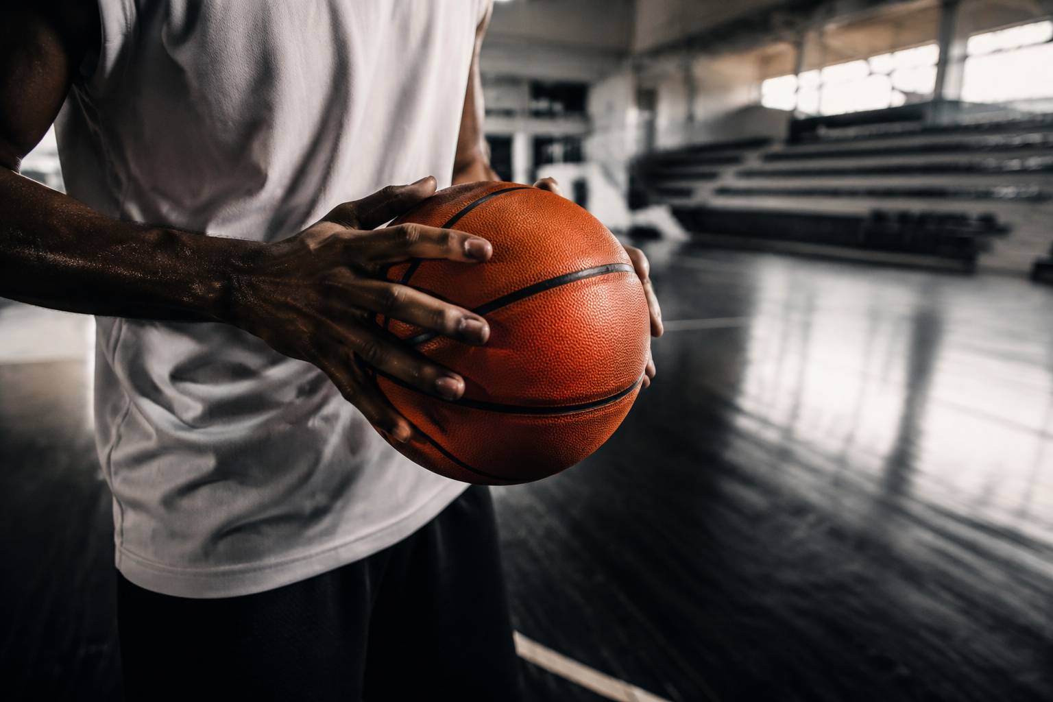 Mains d'un basketteur tenant un ballon en position de passe